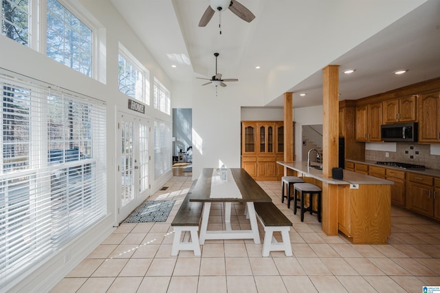 kitchen featuring light tile patterned floors, stainless steel appliances, a sink, tasteful backsplash, and a kitchen bar