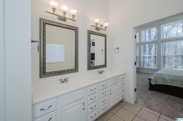 ensuite bathroom with double vanity, ensuite bathroom, a sink, and tile patterned floors