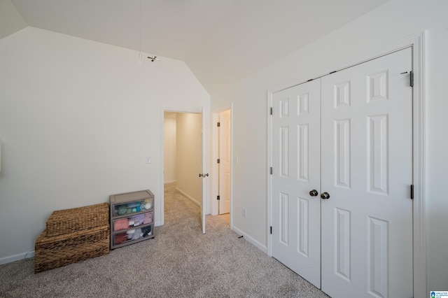 interior space with a closet, carpet flooring, vaulted ceiling, and baseboards