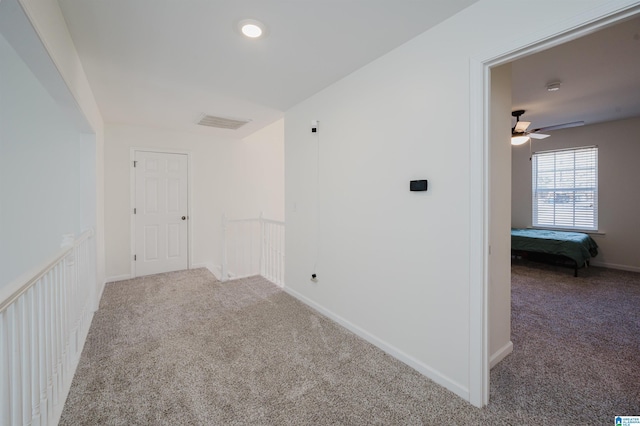 empty room with carpet, visible vents, and baseboards