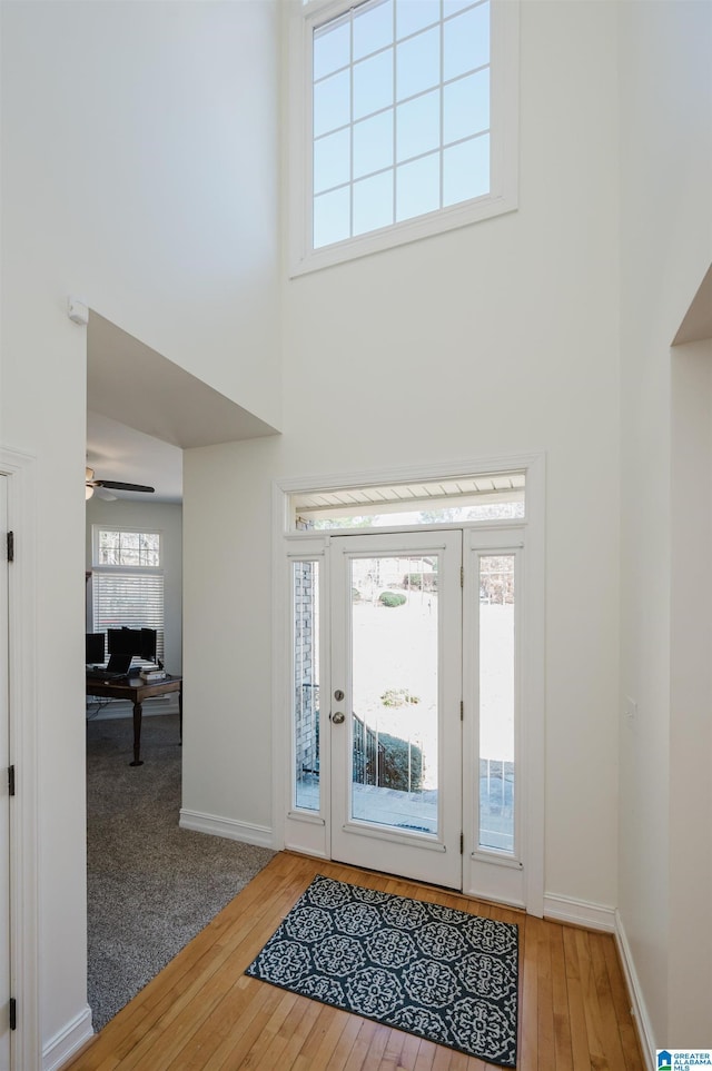 foyer with wood-type flooring, a high ceiling, baseboards, and ceiling fan