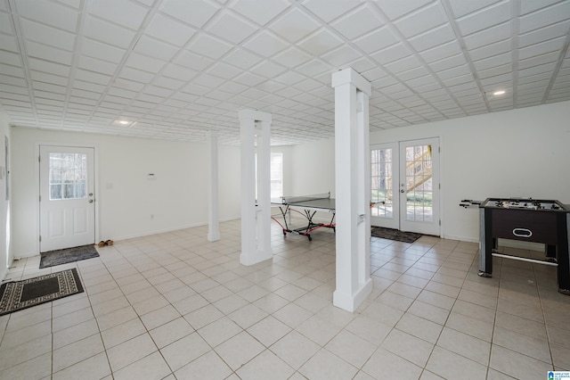 basement featuring light tile patterned floors, french doors, plenty of natural light, and baseboards