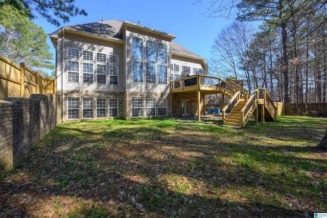 rear view of property featuring a fenced backyard, a yard, a wooden deck, and stairs