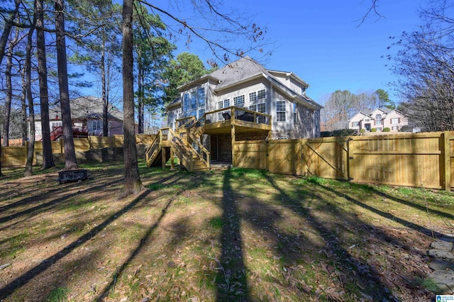 rear view of house with an outdoor fire pit, fence, a wooden deck, and stairs