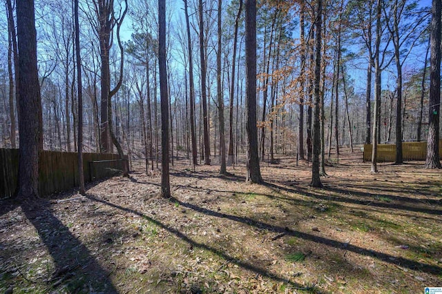 view of yard with fence and a wooded view