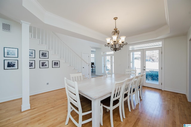 dining area featuring light wood finished floors, visible vents, a raised ceiling, stairs, and french doors