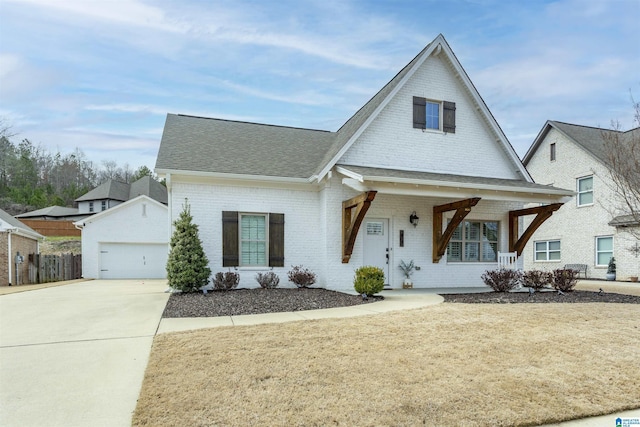 view of front of home with a shingled roof, a porch, fence, a front lawn, and brick siding