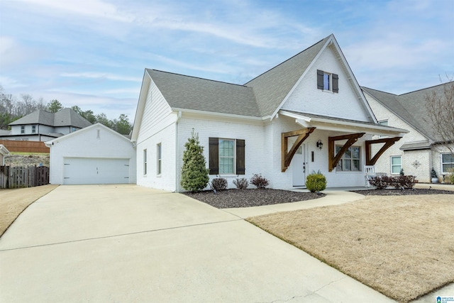 view of front facade featuring a shingled roof, a detached garage, fence, an outdoor structure, and brick siding