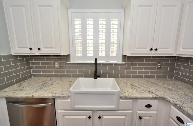 kitchen featuring tasteful backsplash, stainless steel dishwasher, a sink, and white cabinets