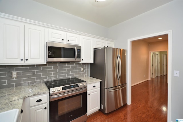 kitchen featuring tasteful backsplash, white cabinets, dark wood-style floors, light stone counters, and stainless steel appliances