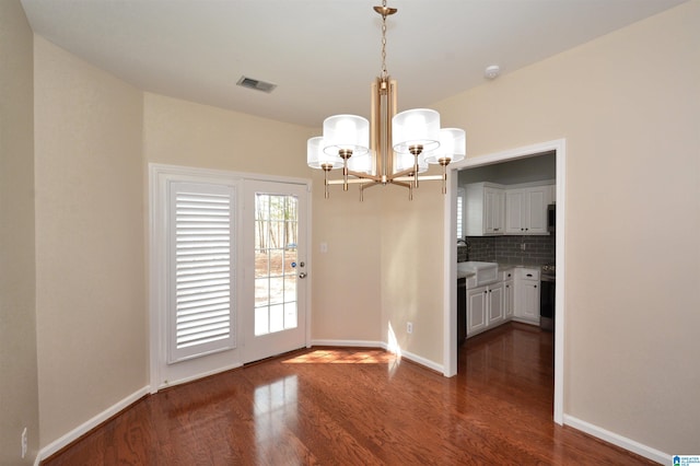 unfurnished dining area with baseboards, dark wood finished floors, visible vents, and an inviting chandelier