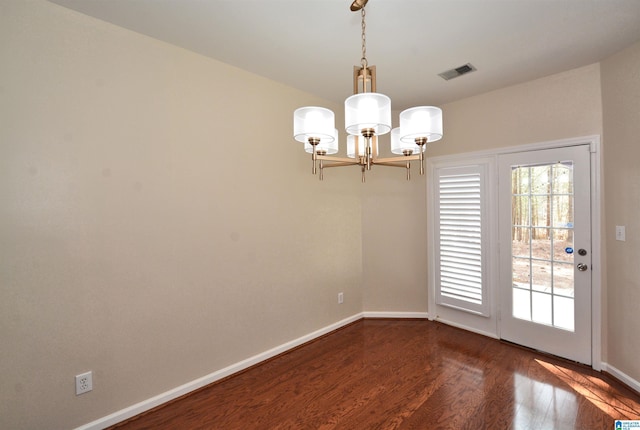 spare room with dark wood-style floors, baseboards, visible vents, and a notable chandelier