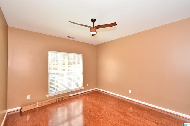 empty room with baseboards, wood finished floors, visible vents, and a ceiling fan