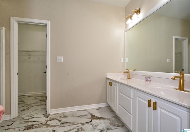 bathroom with marble finish floor, double vanity, a sink, and baseboards