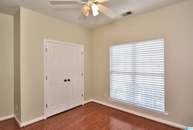 spare room featuring a ceiling fan, visible vents, baseboards, and wood finished floors