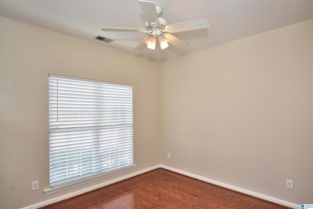 spare room with baseboards, wood finished floors, visible vents, and a ceiling fan