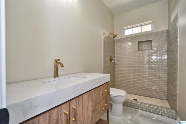 bathroom featuring vanity, a tile shower, and toilet