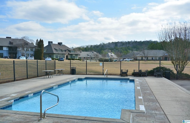 community pool with a yard, a residential view, a patio area, and fence