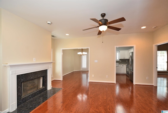 unfurnished living room with dark wood-style flooring, a premium fireplace, a ceiling fan, and baseboards