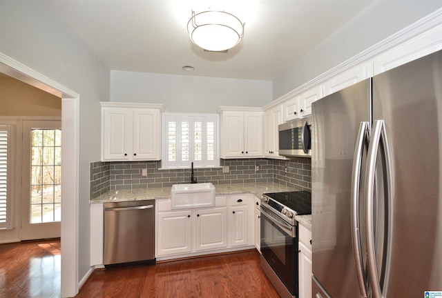 kitchen with dark wood-style flooring, tasteful backsplash, appliances with stainless steel finishes, white cabinetry, and a sink