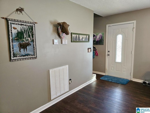 entryway with visible vents, a textured ceiling, baseboards, and wood finished floors