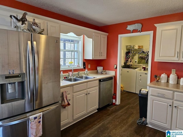 kitchen featuring separate washer and dryer, a sink, white cabinetry, light countertops, and appliances with stainless steel finishes