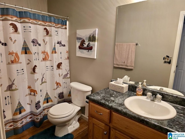 bathroom featuring toilet, curtained shower, wood finished floors, and vanity