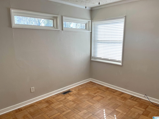 spare room featuring crown molding, visible vents, and baseboards