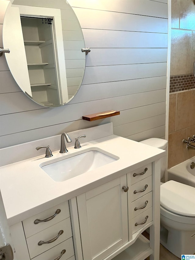 bathroom with shower / tub combination, toilet, wooden walls, and vanity