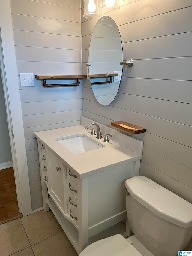 bathroom with toilet, wood walls, tile patterned flooring, and vanity