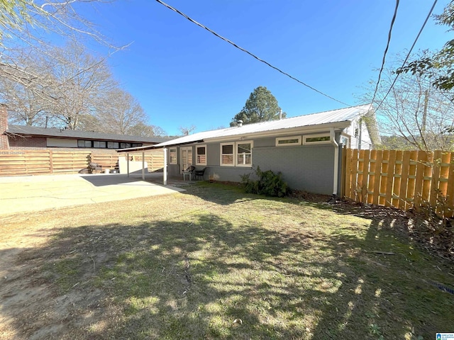 rear view of property featuring metal roof, brick siding, a patio, and fence