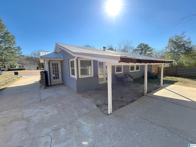 view of front of property with a patio area, fence, metal roof, and stucco siding