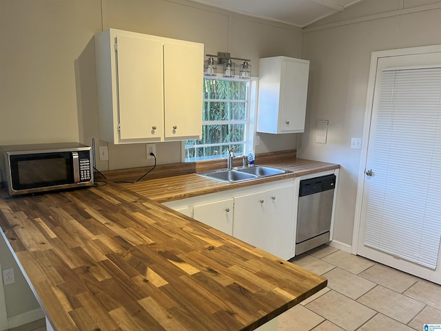 kitchen featuring light tile patterned floors, lofted ceiling, appliances with stainless steel finishes, white cabinets, and a sink