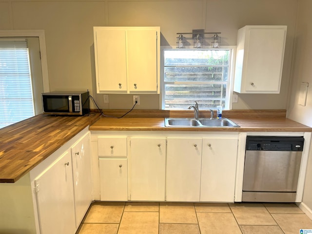 kitchen featuring light tile patterned floors, white cabinets, butcher block counters, appliances with stainless steel finishes, and a sink