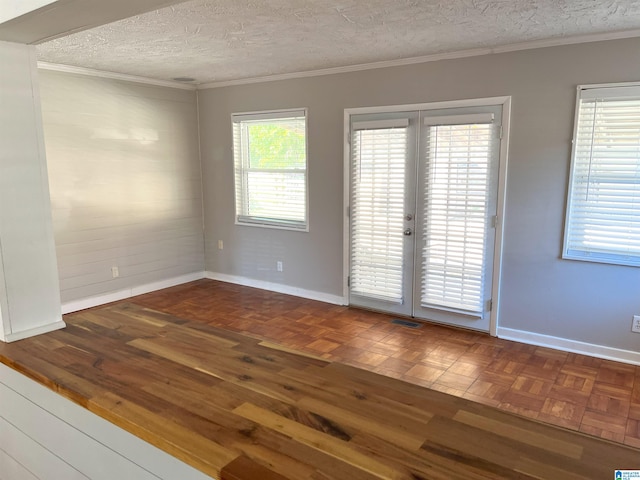 unfurnished room with a textured ceiling, visible vents, baseboards, french doors, and ornamental molding