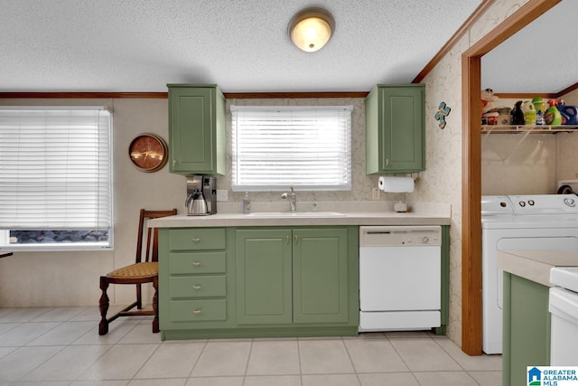 kitchen with white dishwasher, a sink, washer and dryer, and green cabinetry