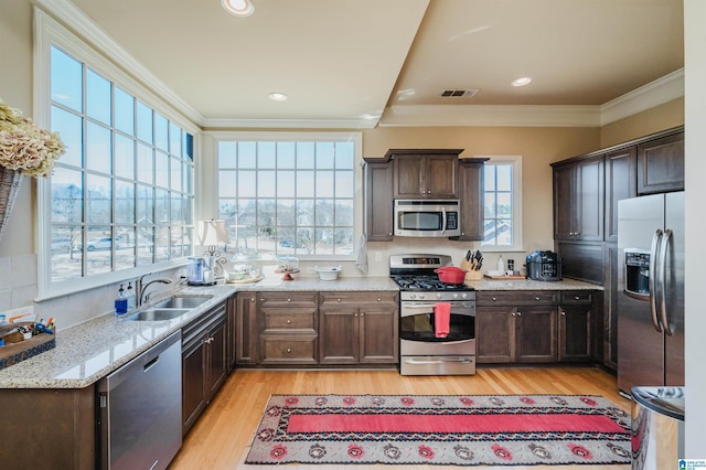 kitchen featuring visible vents, appliances with stainless steel finishes, ornamental molding, dark brown cabinets, and a sink