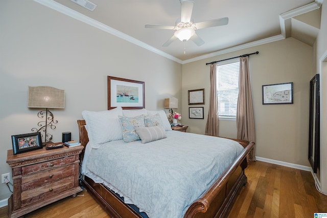 bedroom featuring baseboards, wood finished floors, visible vents, and crown molding