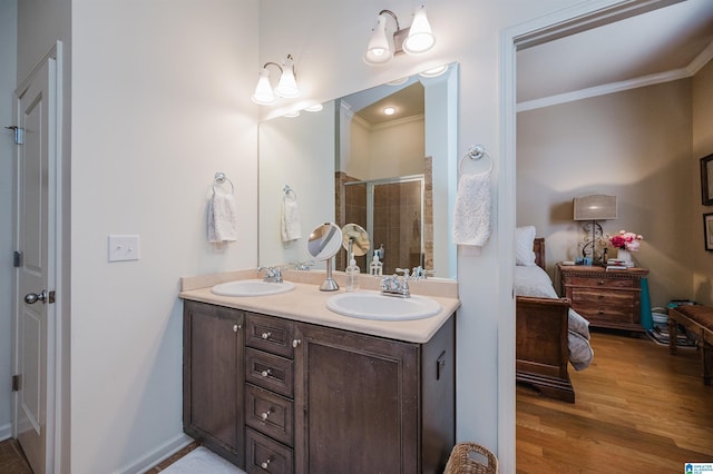 ensuite bathroom featuring crown molding, a stall shower, a sink, and connected bathroom