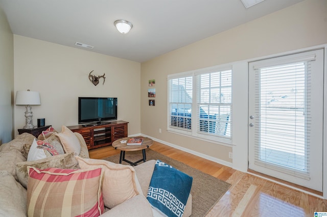 living area with baseboards, visible vents, and wood finished floors