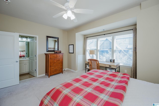 bedroom with ceiling fan, ensuite bathroom, light colored carpet, visible vents, and baseboards