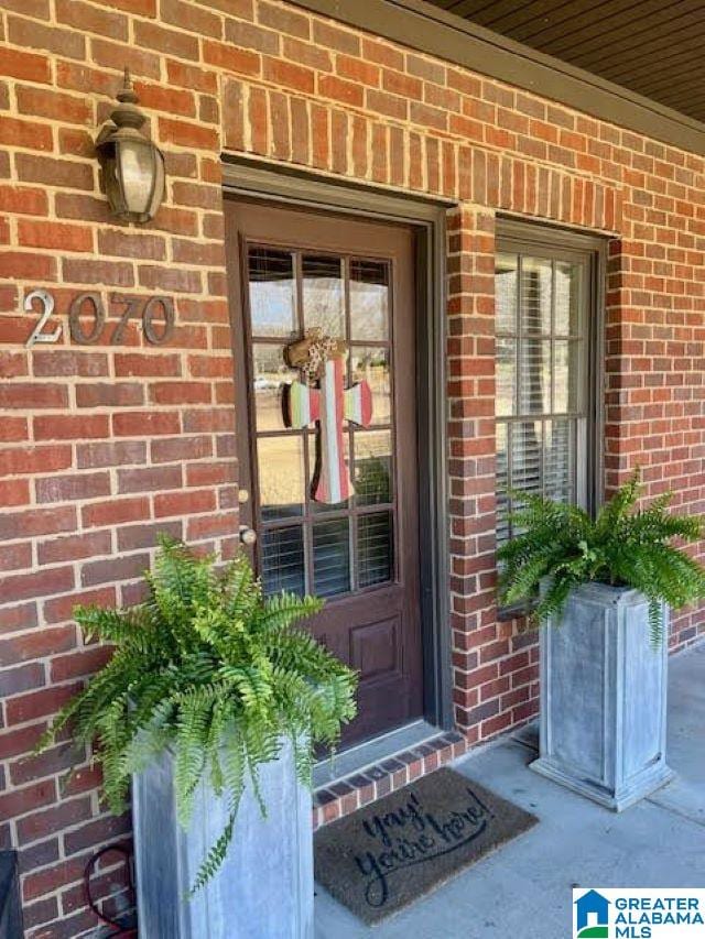 doorway to property with brick siding