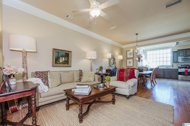 living area featuring wood-type flooring, ceiling fan with notable chandelier, visible vents, and ornamental molding