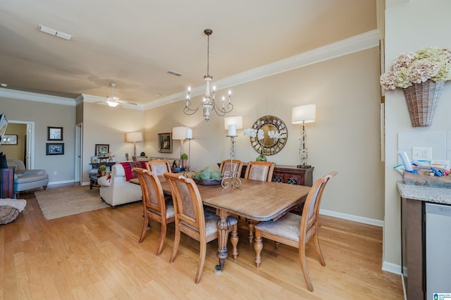 dining room with light wood finished floors, visible vents, crown molding, and ceiling fan with notable chandelier