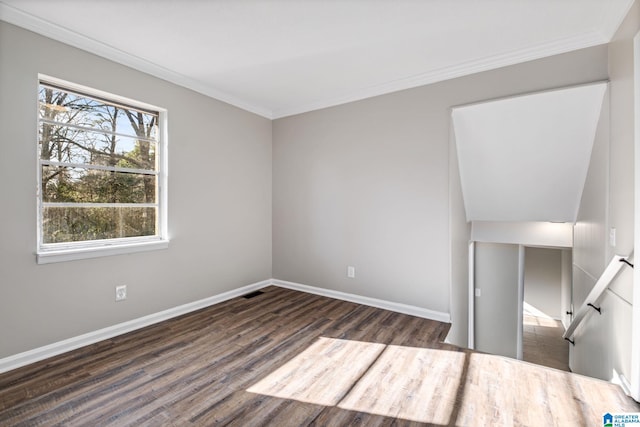 empty room featuring crown molding, baseboards, and wood finished floors