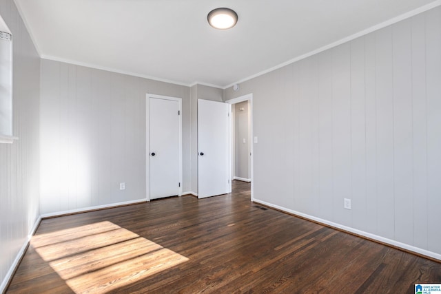 empty room with baseboards, dark wood-type flooring, and crown molding