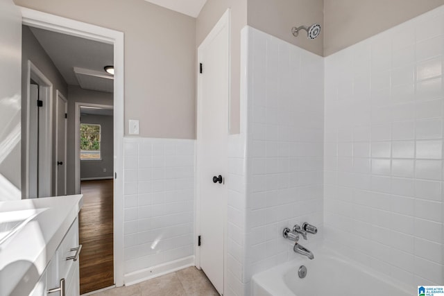 bathroom with tile walls, wainscoting, tub / shower combination, vanity, and tile patterned flooring