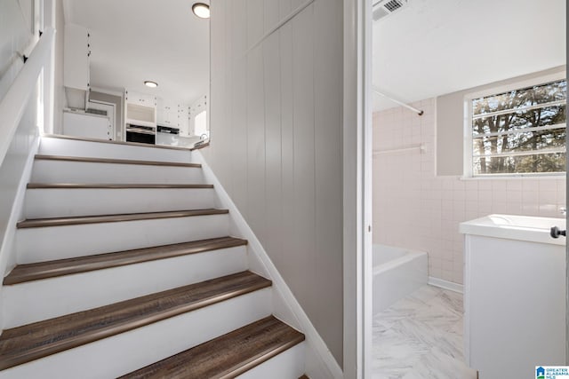 stairs with marble finish floor, visible vents, and baseboards