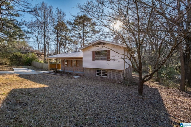 view of front of property featuring metal roof, brick siding, a porch, and fence