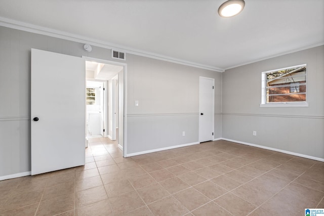 unfurnished room with light tile patterned floors, baseboards, visible vents, and crown molding